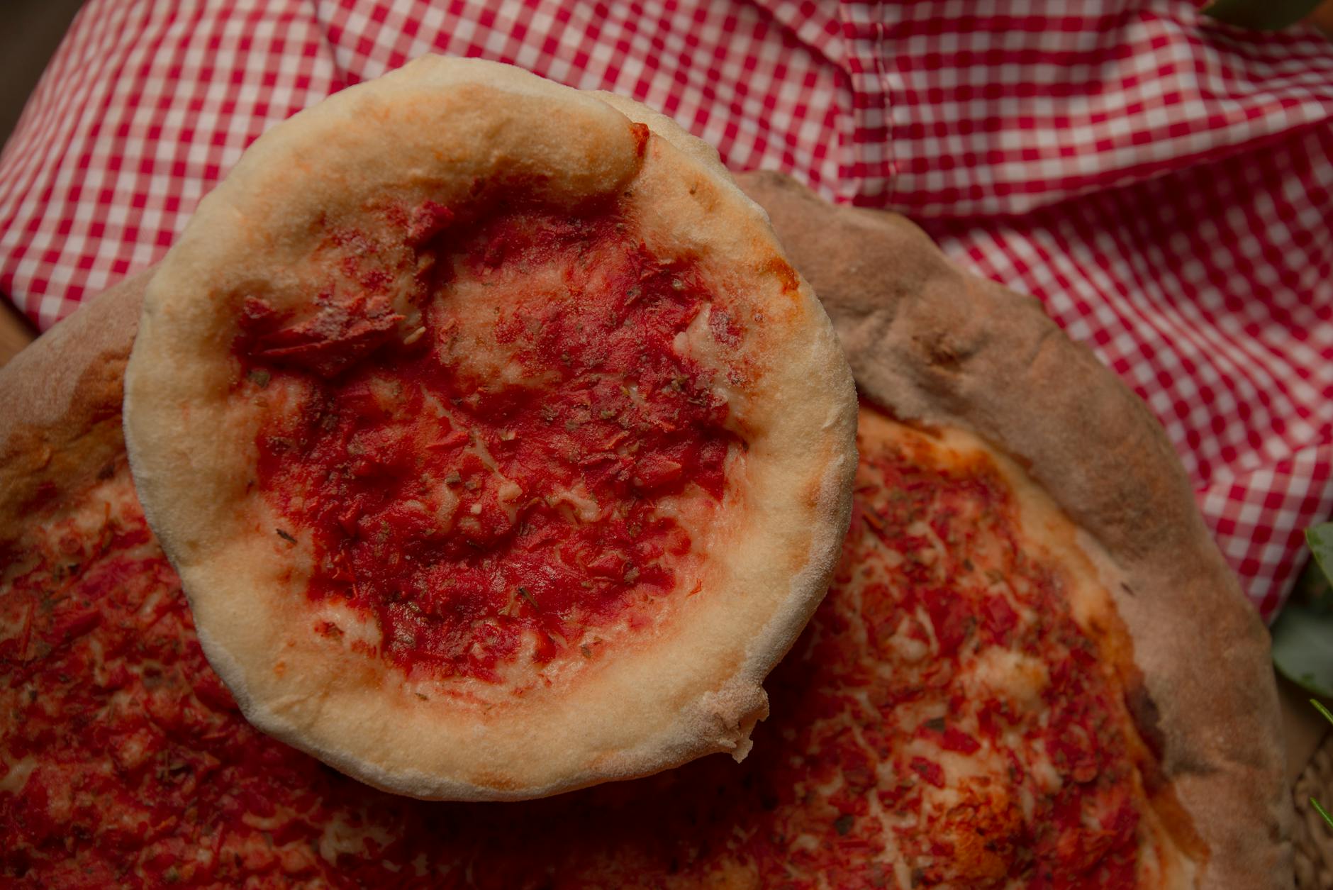 Domowa pizza na cienkim cieście z sosem pomidorowym na kratkowanym obrusie
