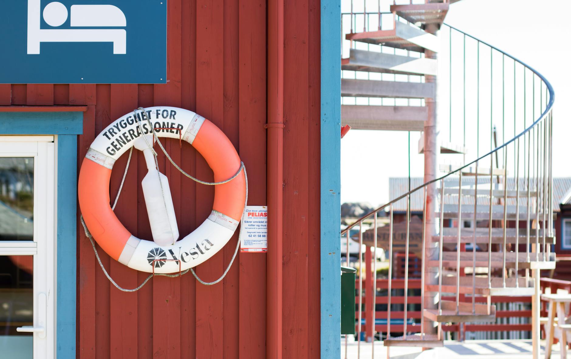 Koło ratunkowe na czerwonej ścianie przy metalowych schodach zewnętrznych