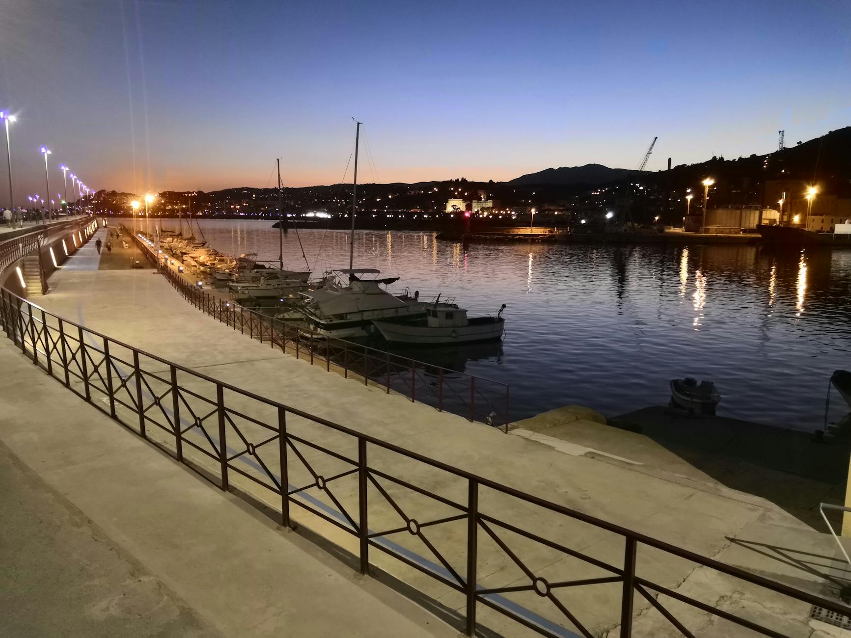 Wieczorna marina w Kristiansand z łodziami i światłami miasta odbitymi w wodzie