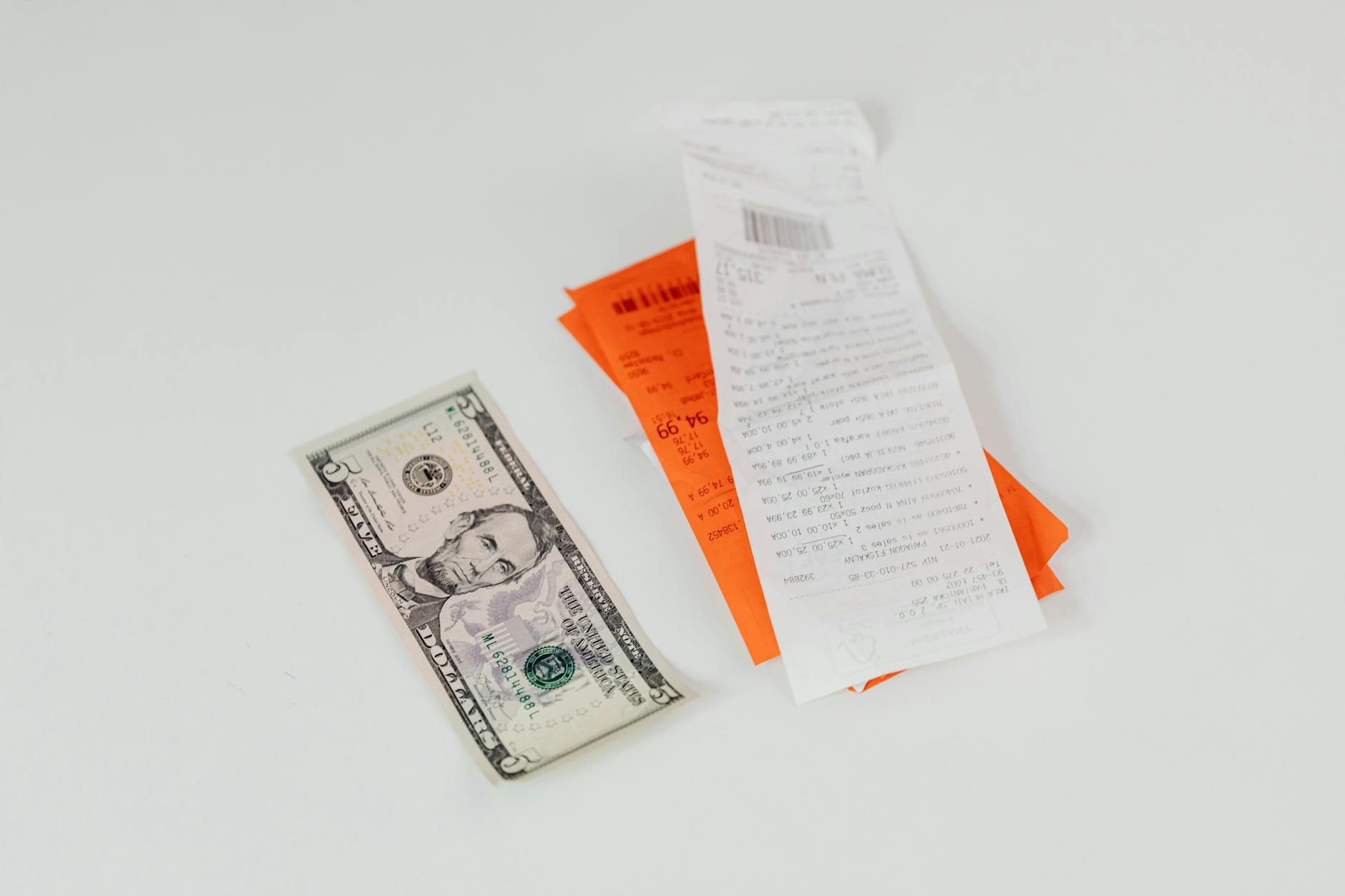 Banknot pięciodolarowy obok paragonów na białym tle