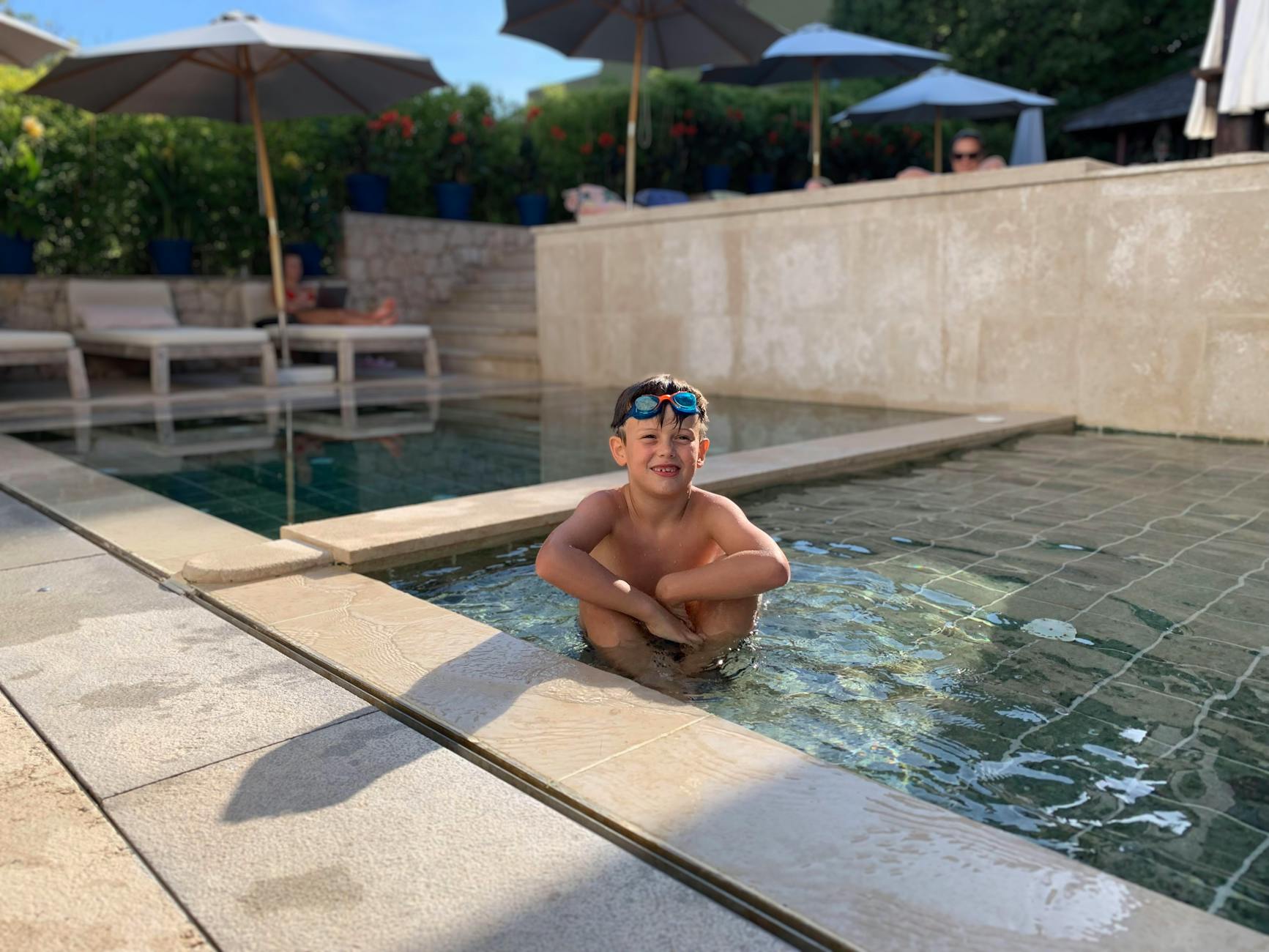 Dziecko w okularach pływa w odkrytym hotelowym basenie