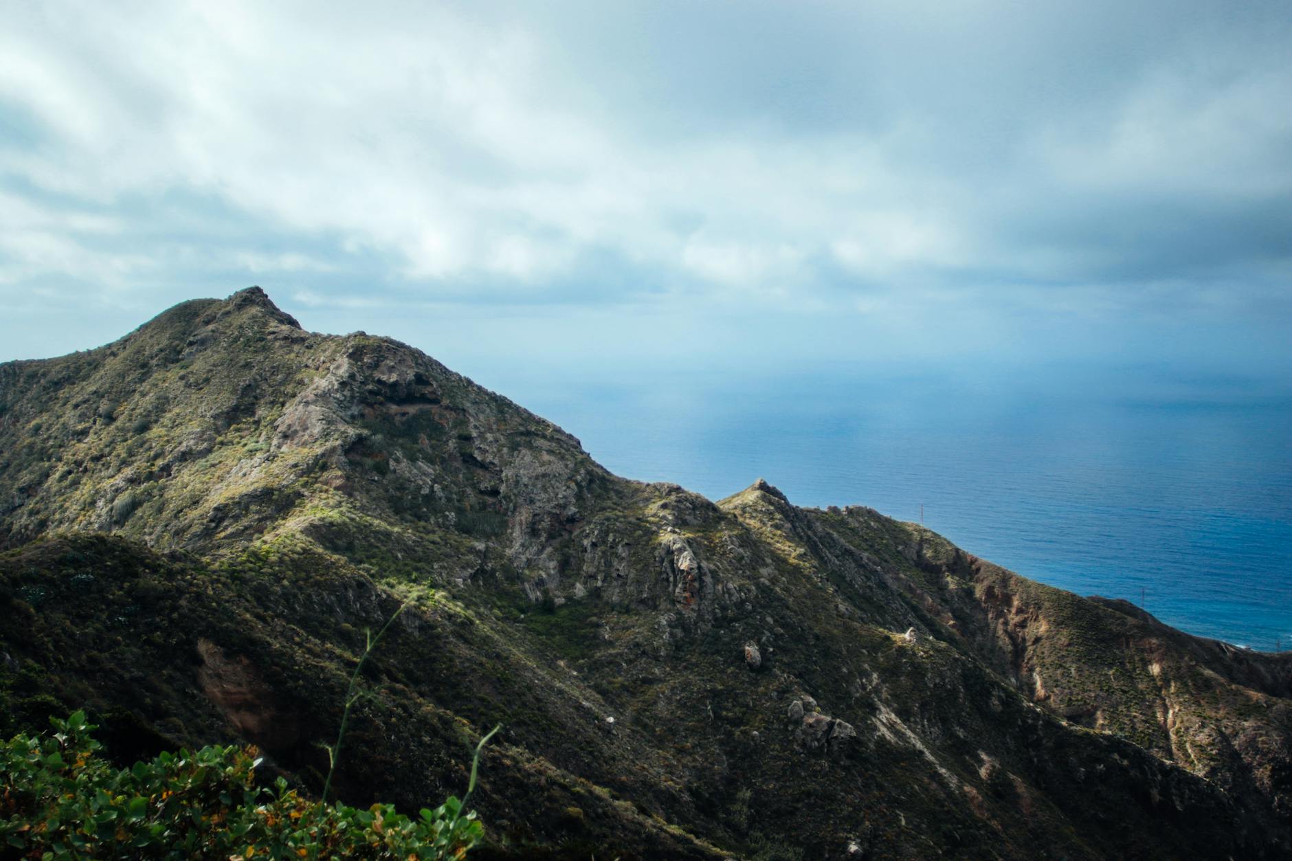 Górskie pasmo schodzące do spokojnego morza pod zachmurzonym niebem