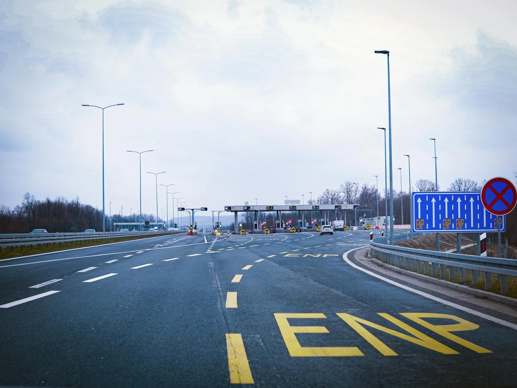 Ceny paliwa i opłaty drogowe w Norwegii: ile kosztuje przejazd w okolice Kristiansand Pusta autostrada do bramki poboru opłat w Norwegii pod pochmurnym niebem