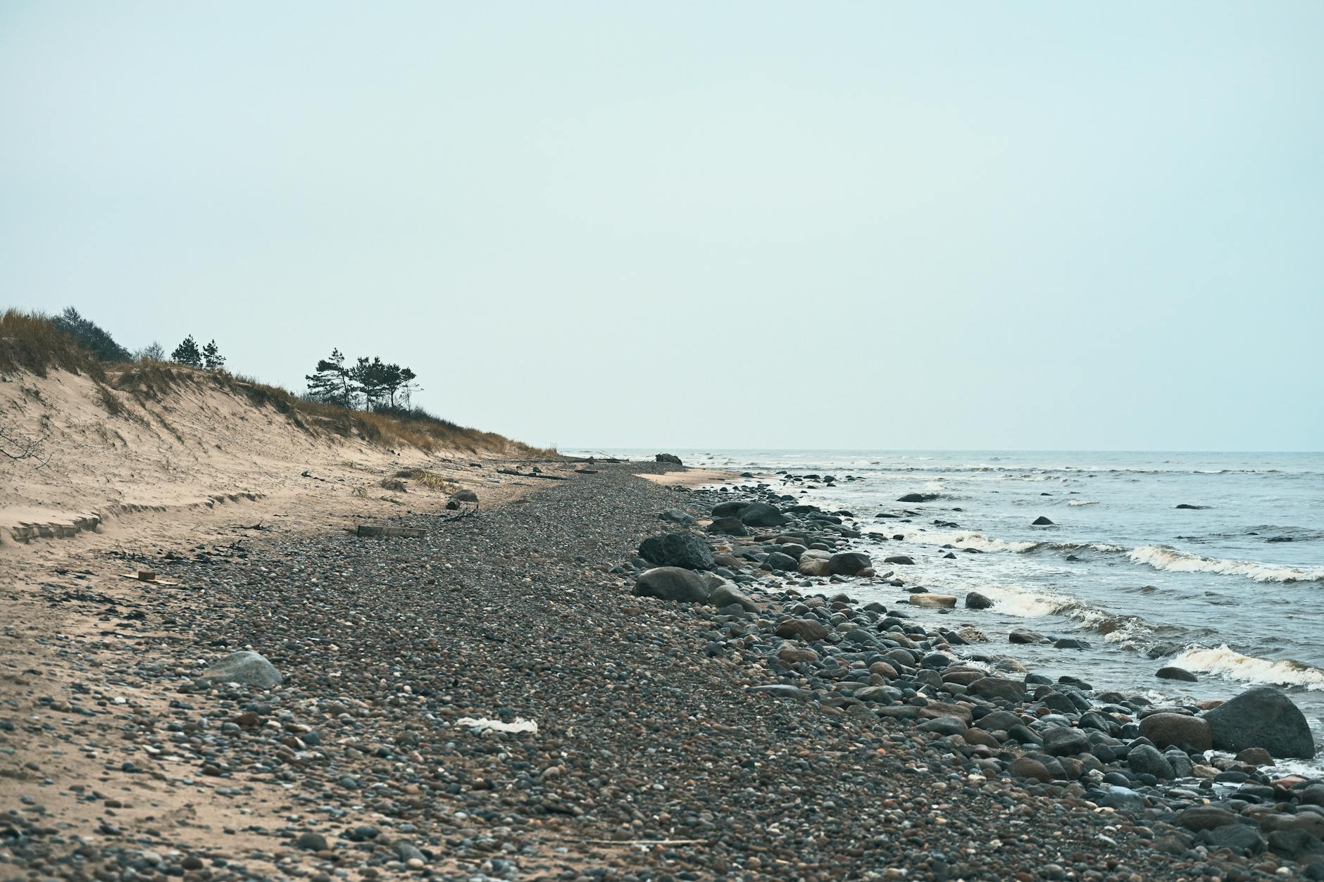Skalista, pusta plaża nad spokojnym morzem poza letnim sezonem