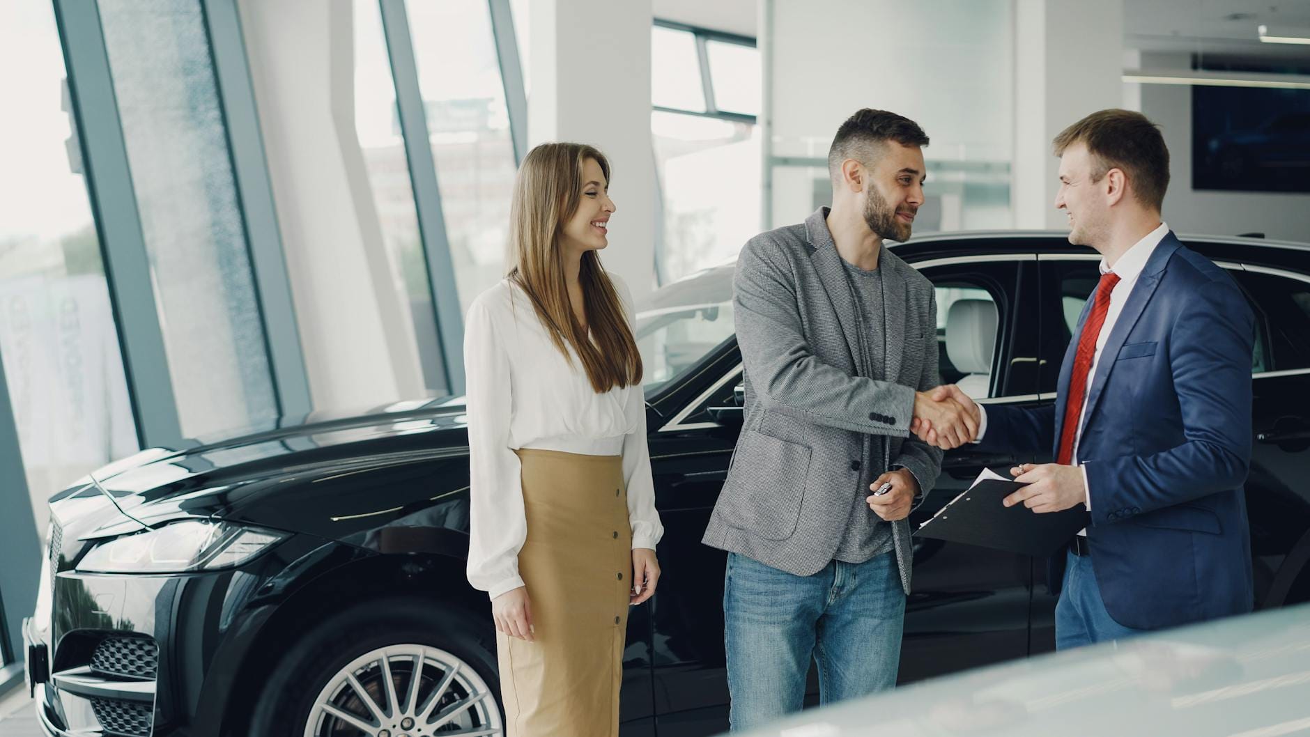 Klient podaje dłoń dealerowi przy odbiorze wynajętego samochodu