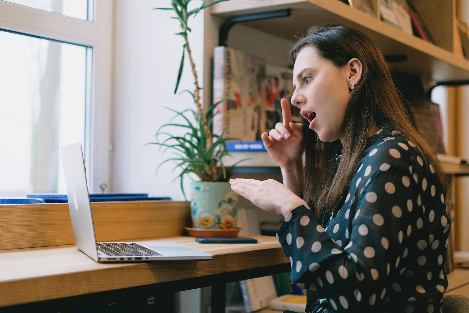 Kobieta uczy się języka migowego przy laptopie w domu