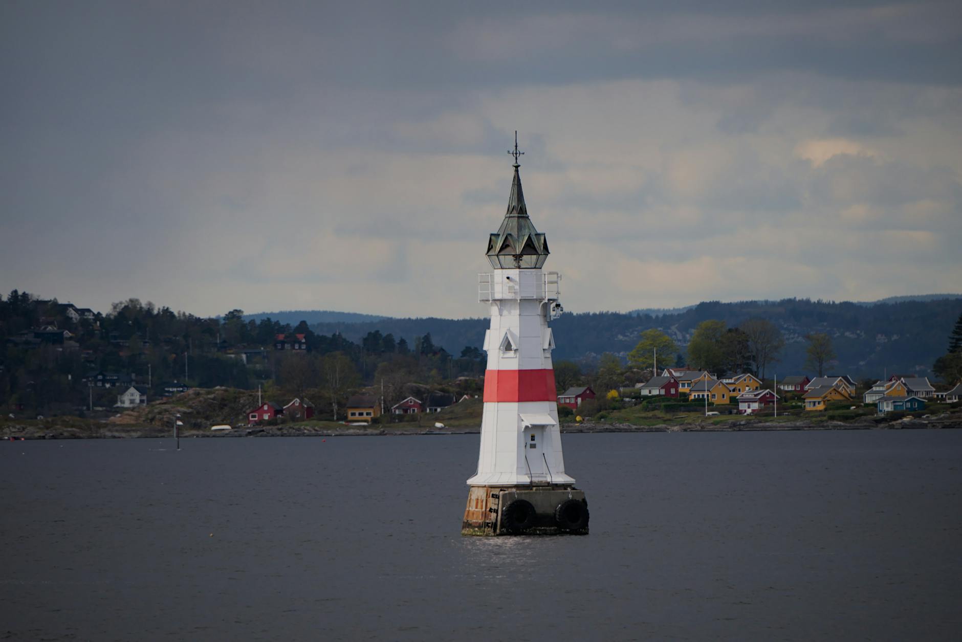 Latarnia morska na wybrzeżu Sørlandet z domkami nad zatoką