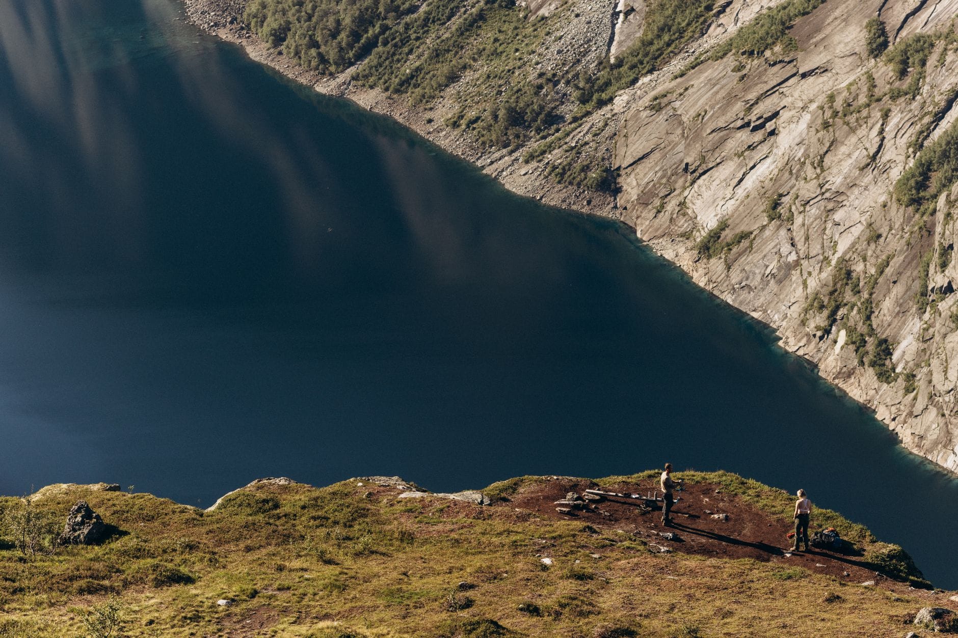 Dwoje turystów na skalnej półce z widokiem na norweski fiord