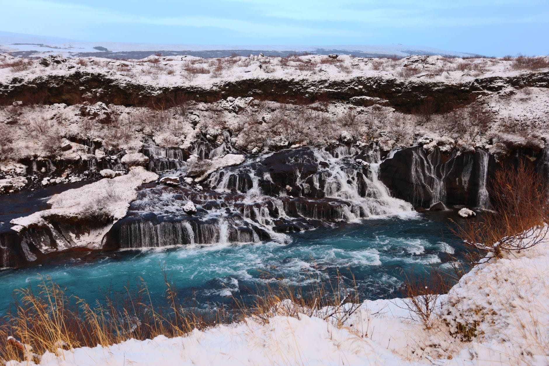 Zimowy wodospad Hraunfossar w ośnieżonym krajobrazie Islandii