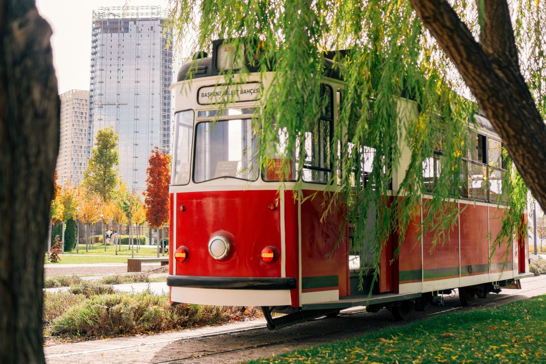 Czerwony, zabytkowy tramwaj jedzie jesienią między wieżowcami